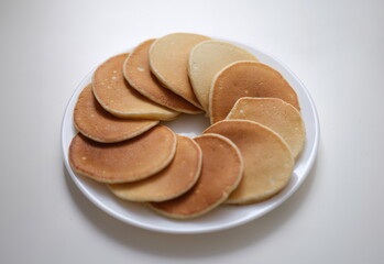 Flour sweet round fritters on white plate. Cooking pancakes concept