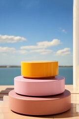 A stack of three pink and yellow  product display podiums for natural product. Circular shape base. Sea on background.