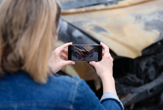 insurance agent or investigator takes picture on smartphone of car after arson. Transport insurance or criminal offense concept