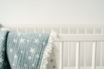 Soft blue muslin blanket hanging on a baby's bed - obrazy, fototapety, plakaty