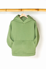 Green sweatshirt hanging on a wooden bamboo hanger, front view. The concept of modern comfortable sportswear.
