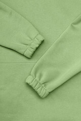Green background of warm knitted sweatshirt and sleeves with elastic bands.