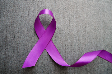 Purple ribbon with pancreatic cancer awareness on a luxury gray background.