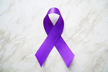 Purple ribbon with pancreatic cancer awareness on a luxury gray background.