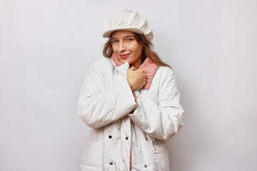 A beautiful girl is dressed in a white autumn raincoat and a white warm hat. © Vasyl