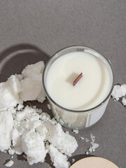 Scented candle in glass with wooden lid on gray background. Candle and soy or coconut wax