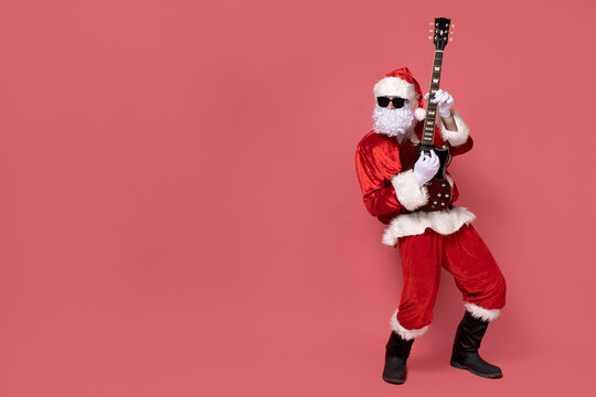 Cheerful Santa Claus playing the guitar on a pink background.