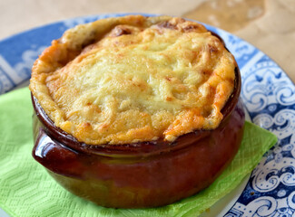 Traditional Greek style moussaka prepared and served in clay pot. Close-up. Selective focus.