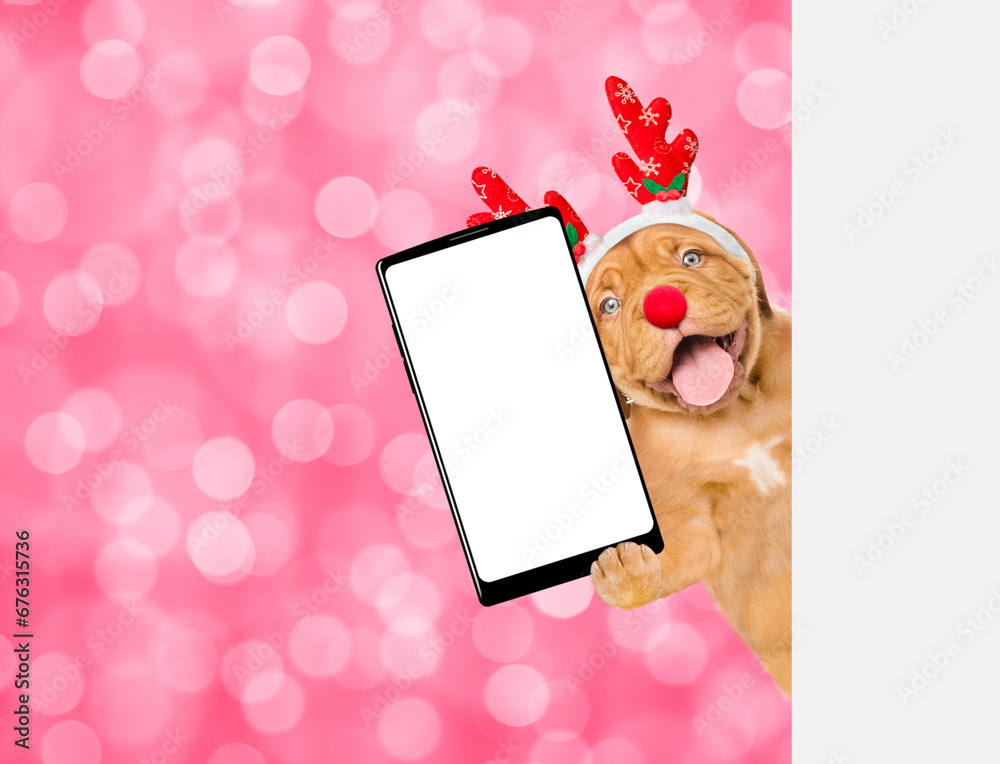 Poster happy mastiff puppy dressed like santa claus reindeer rudolf holds big smartphone with empty screen 