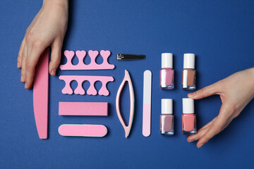 Tools for nail art and female hands on blue background, top view
