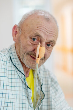 Patient with nasogastric tube on hospital bed waiting for treatment. Positive close up of an elder man waiting for an operation. Enthusiastic approach to hospital treatment.