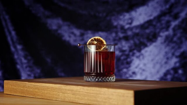 Bartender putting cherry into negroni cocktail. Dark background. Gin, sweet vermouth, red Campari bitter liqueur. Concept of cocktails, alcohol drink, bar, taste, menu, pop art style.