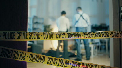 The back view of two detectives standing at the crime scene and looking at the dead body