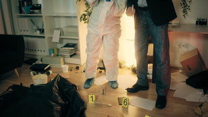 The detective and the forensic expert are discussing the crime scene while examining the evidence