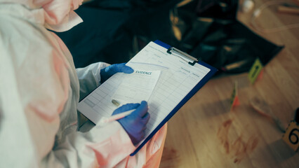 A lab analyst is filling out reports and documenting evidence at the crime scene during a murder...