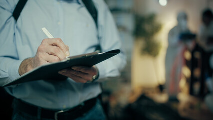 In a close-up shot, a detective is filling out papers while forensic experts collect evidence