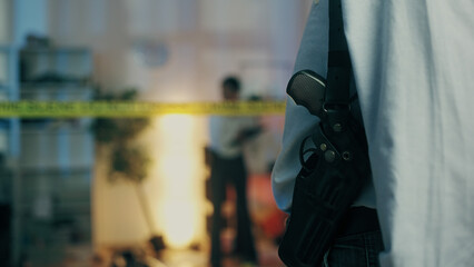 A detective with a gun in a holster is visiting the crime scene, part of a murder investigation, seen from the back - obrazy, fototapety, plakaty