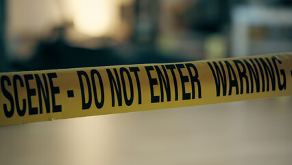 A close-up view of the warning tape at the crime scene in a trashed room, indicating a police investigation