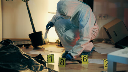 An attentive worker from the forensic laboratory is collecting evidence while examining the crime scene