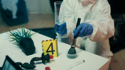 A lab analyst is dusting glass for fingerprints at the crime scene during the investigation