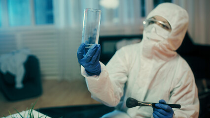 A forensic expert is looking for fingerprints on glass at the crime scene using a special dusting...