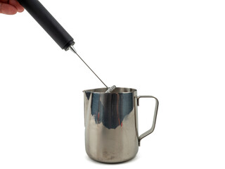 Automatic milk foam maker. Metal milk mug and electric milk frother isolated on a white background.