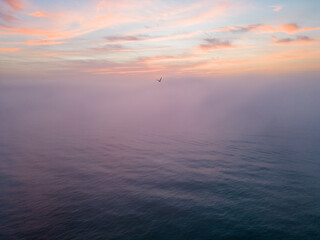 Aerial view of a sunrise sea with a blanket of morning fog and morning sunbeams shining through