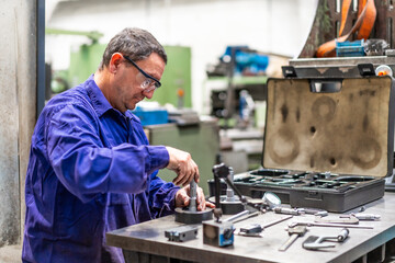 Factory worker operator in the numerical control sector checking the equipment, metal industrial...