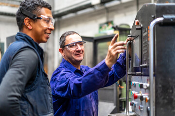 Instructor teaching the trade to a metal industrial factory worker in the numerical control sector