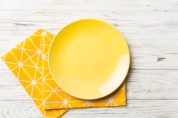 Top view on colored background empty round yellow plate on tablecloth for food. Empty dish on napkin with space for your design
