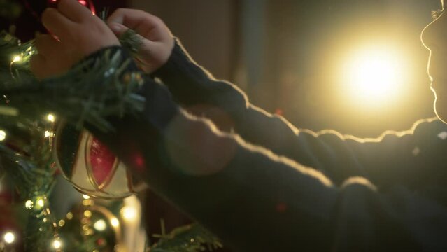 Kid decorating christmas tree with balls 
