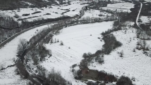 Footage of a snow covered countryside in mountion from above