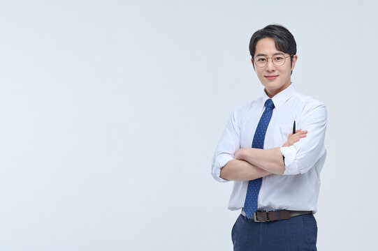 A young, handsome Asian man wearing glasses and a dress shirt and tie is holding a pen and explaining about business.