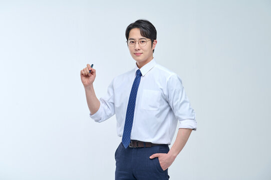 A young, handsome Asian man wearing glasses and a dress shirt and tie is holding a pen and explaining about business.