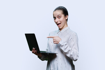 Teenage girl student using laptop, on white background, pointing at screen