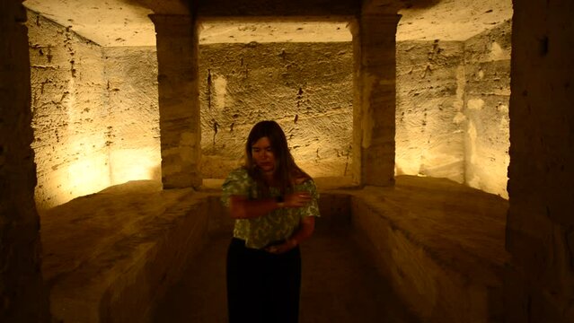 Woman invokes a ritual inside a cave. Girl does an energy cleaning mudra