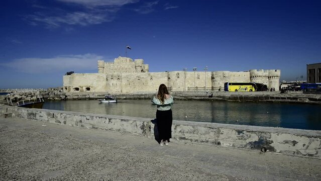 Woman takes a photo of Citadel of Qaitbay in Alexandria, Egypt. Tourist Castle