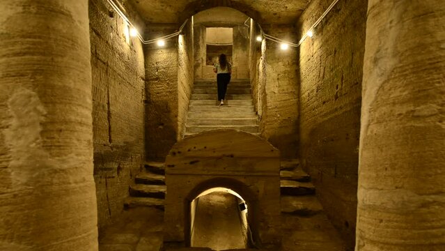 Travel girl explores catacombs of Kom El Shoqafa in Alexandria Egypt. Woman upstairs in Mysterious cave