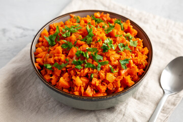 Homemade Smoky Spiced Carrot Rice with Parsley in a Bowl, side view.