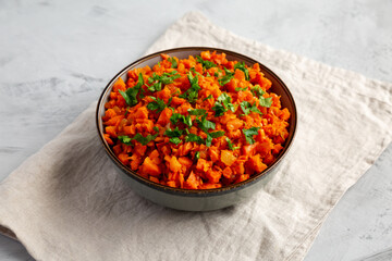 Homemade Smoky Spiced Carrot Rice with Parsley in a Bowl, side view.