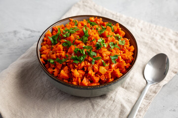 Homemade Smoky Spiced Carrot Rice with Parsley in a Bowl, side view.