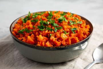 Homemade Smoky Spiced Carrot Rice with Parsley in a Bowl, side view.