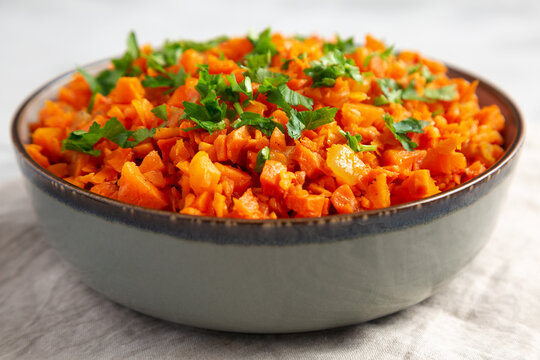 Homemade Smoky Spiced Carrot Rice with Parsley in a Bowl, side view.