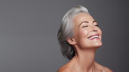 Beautiful aging young looking and smiling woman. Advertising concept for cosmetics and beauty products. Gray hair and healthy skin.