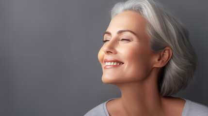 Fototapeta premium Beautiful aging young looking and smiling woman. Advertising concept for cosmetics and beauty products. Gray hair and healthy skin.