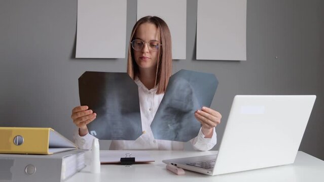Professional woman radiologist working for diagnostic examinations expertise in radiology examines X-ray images comparing providing precise diagnoses to ensure optimal healthcare for the patient.
