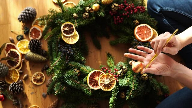 Artist applies paint to an onion for a Christmas wreath