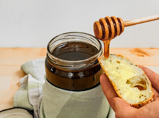 Kromka chleba z masłem polewana plynnm świeżym miodem pszczelim
