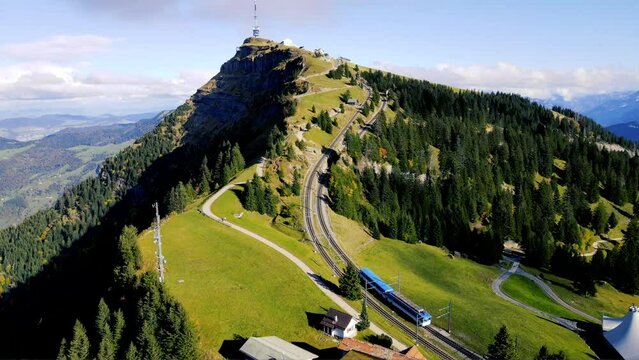 panoramic aerial view of spectacular high-altitude funicular descending from Rigi Kulm Peak towards Rigi Staffel Station in a green alpine scenery in Switzerland 
