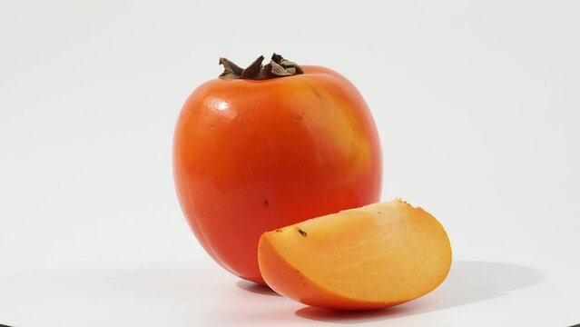 Ripe persimmon rotates on a white background. Persimmon close-up on white.